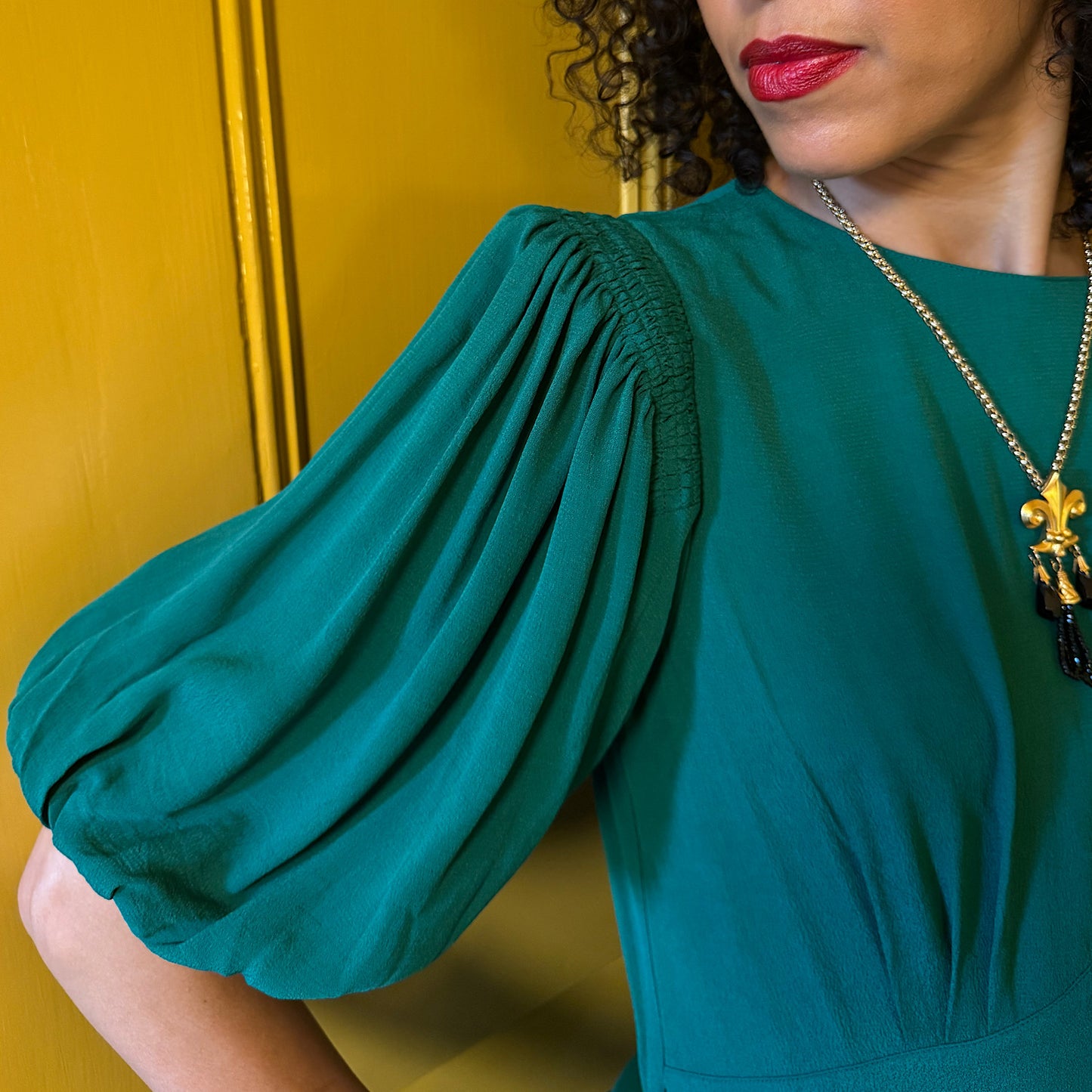 Clemence dress in jewel green viscose crepe with contrast black satin belt.