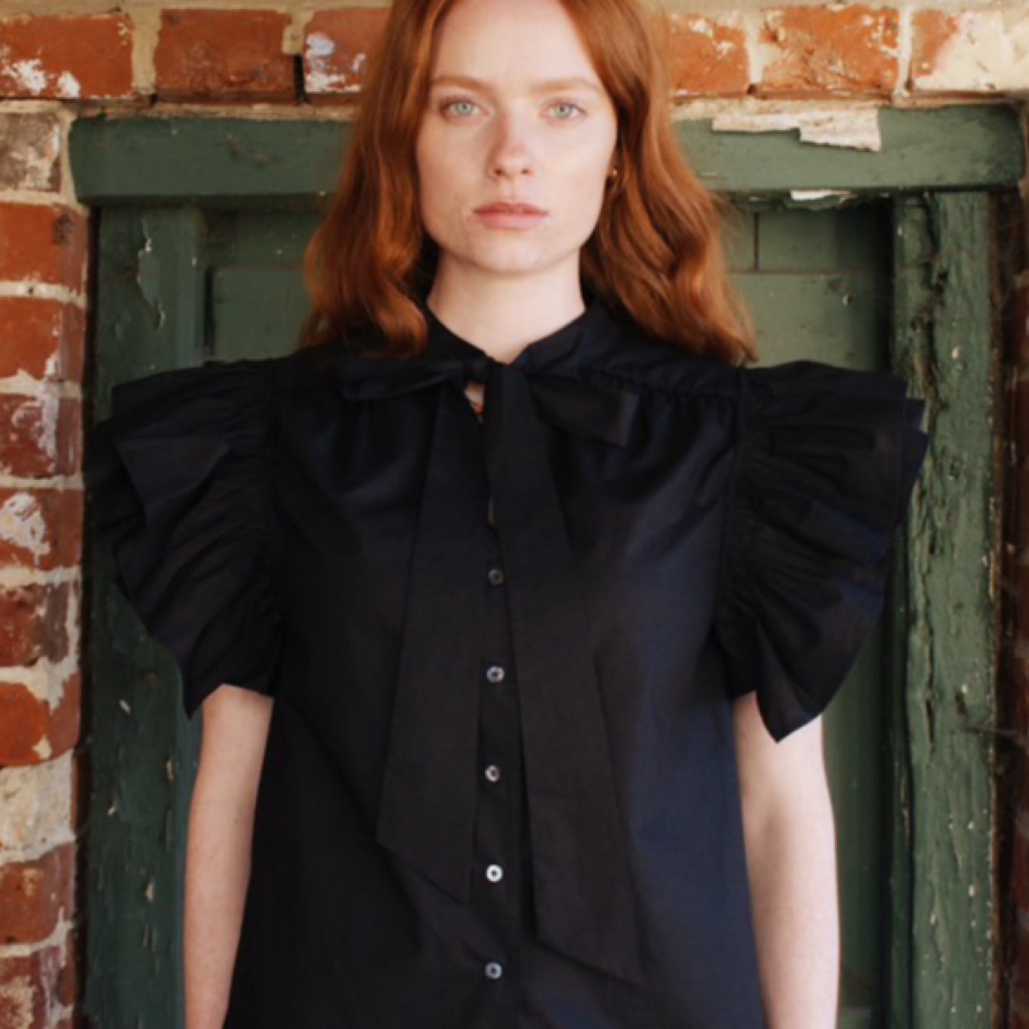 Mia frill blouse in plain black cotton lawn with frill sleeves and tie neck.