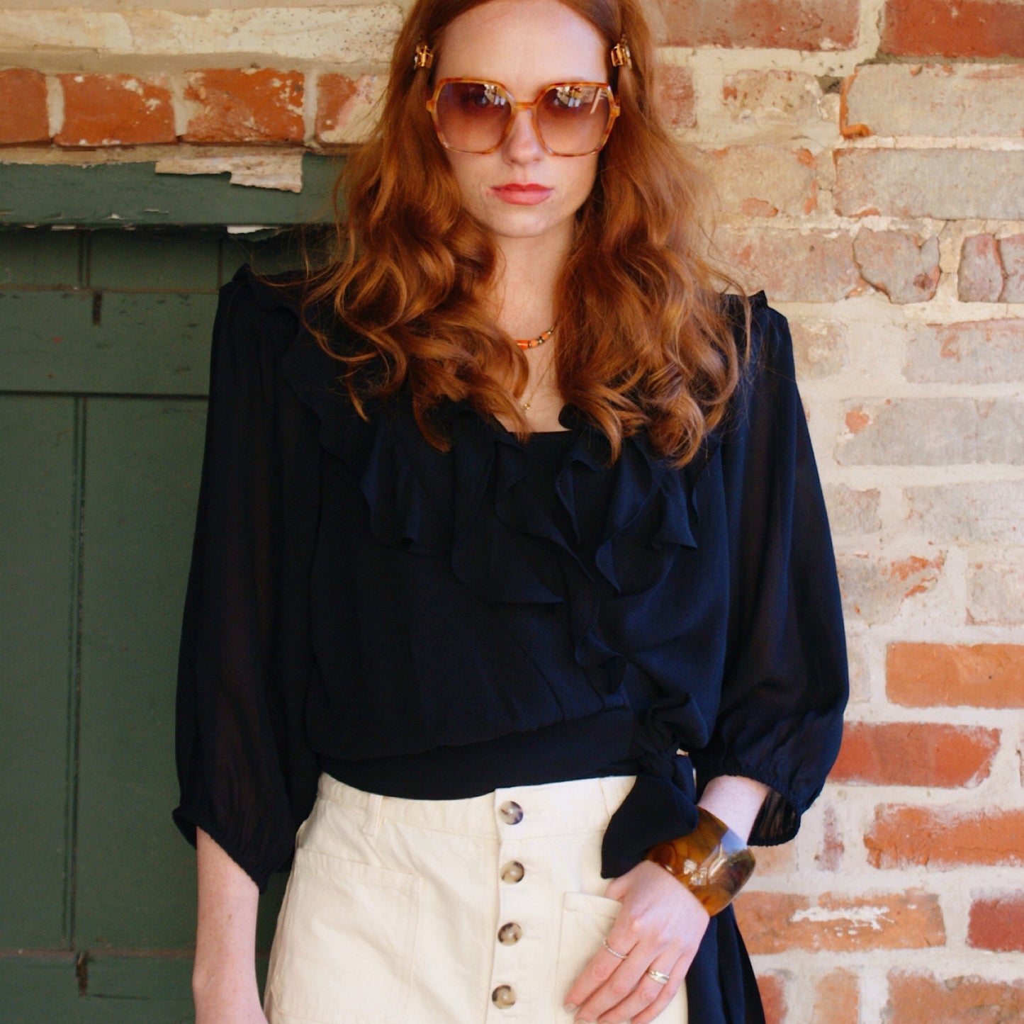 Phoebe blouse in black viscose georgette with wrap front and ruffles.